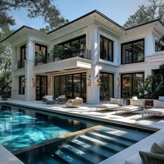 a large house with a swimming pool in front of it and lots of windows on the side