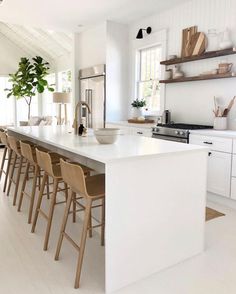 a large white kitchen with lots of counter space and stools around the center island