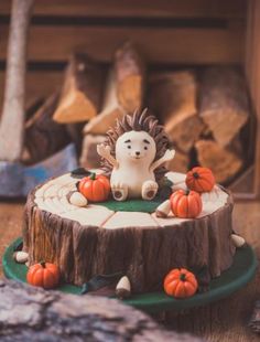 a hedgehog cake sitting on top of a green plate with pumpkins around it