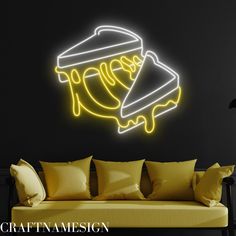 a yellow couch sitting in front of a black wall with a neon sign on it