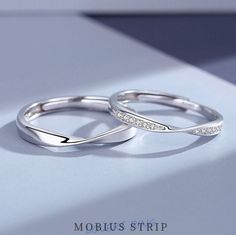 two white gold wedding rings with diamonds on them, sitting on top of a table