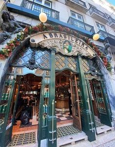 the entrance to a building with green doors and windows on both sides is decorated with flowers