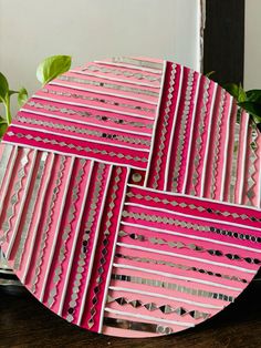 three pink plates sitting on top of a wooden table next to a potted plant