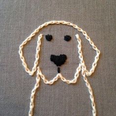 a close up of a dog's face on a piece of cloth with yarn