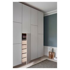 an empty room with white cupboards and drawers in the corner, along with a rug on the floor