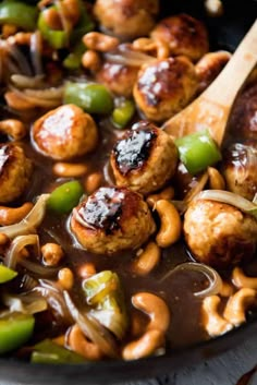 a skillet filled with meatballs, peppers and onions next to a wooden spoon