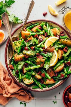 a bowl filled with asparagus, lemons and other vegetables next to orange juice