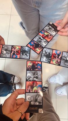 several people are playing with some pictures on the floor and one person is pointing at them