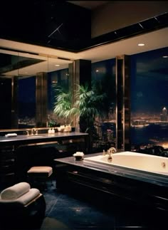 a large bath tub sitting in the middle of a bathroom next to a window with city lights on it