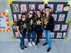 three girls are posing in front of a wall decorated with stars