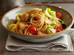 pasta with shrimp, zucchini and cherry tomatoes in a bowl on a table