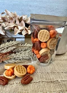 nuts and waffles are in a container on a table next to some dried leaves