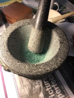 a stone mortar bowl with a metal pole sticking out of it's center, on top of newspapers