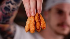 a man holding up some fried food in his hand