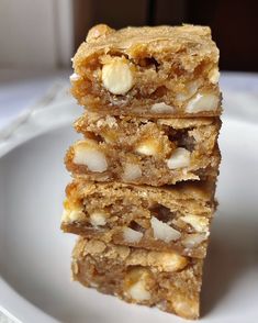 three pieces of food stacked on top of each other in front of a plate full of nuts