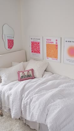 a white bed sitting in a bedroom next to two pictures on the wall above it