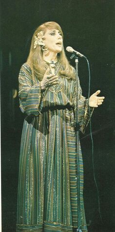 a woman standing in front of a microphone with her hands on her hips and wearing a striped dress