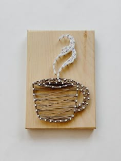 a piece of art made out of wood and wire with a coffee cup on it