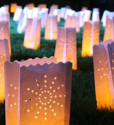 many paper bags are lit up in the grass with small lights on them as well