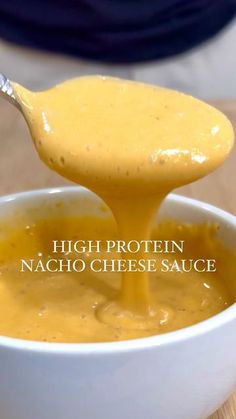 a spoon full of cheese sauce being poured into a white bowl with the words high protein nacho cheese sauce