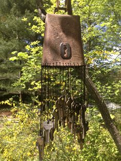 an old wind chime hanging from a tree in the woods with lots of keys attached to it