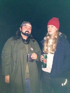 two people standing next to each other holding beer cans