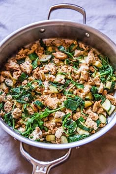 a pan filled with meat and vegetables on top of a white cloth covered tablecloth