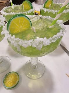 three margaritas with lime slices and white sugar on the rim, sitting on a table