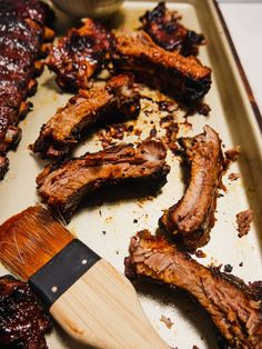 bbq ribs and barbecue sauce on a baking sheet with a spatula next to them