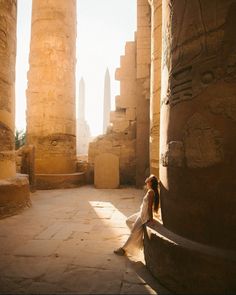 a woman is sitting in an ancient building