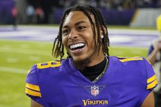 a man with dreadlocks and a football uniform on is smiling at the camera