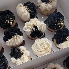 cupcakes with black, white and gold decorations in a box