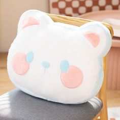 a white teddy bear pillow sitting on top of a wooden chair