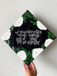 someone is holding up a graduation cap with flowers on it