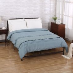 a bed sitting on top of a wooden floor next to a white brick wall in a bedroom