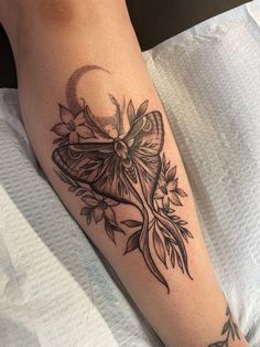 a woman's leg with a bow and flowers tattoo on her left calf area