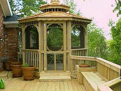 a wooden gazebo sitting on top of a wooden deck next to potted plants