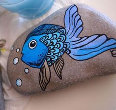 two rocks with fish painted on them next to a blue water bottle and other items