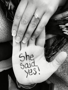 two hands holding each other with the words she said yes written on their palms