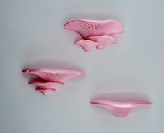 three pieces of pink plastic sitting on top of a white table next to each other