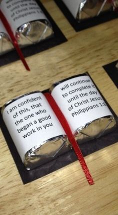 an open book with a red ribbon tied around it sitting on top of a wooden table