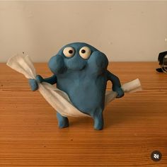 a blue figurine holding a piece of paper on top of a wooden table