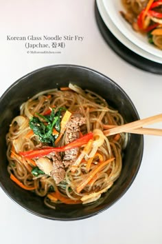 a bowl filled with noodles, meat and veggies next to chopsticks