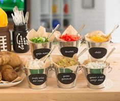 a wooden table topped with metal buckets filled with different types of food and utensils