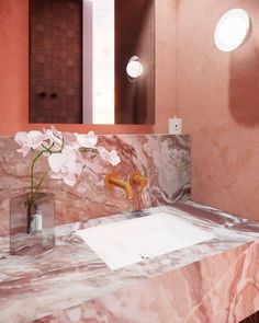 a bathroom with pink walls and marble counter top, gold faucet sink and mirror