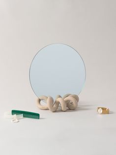 a mirror and comb sitting next to each other on a white surface with a circular object in the foreground