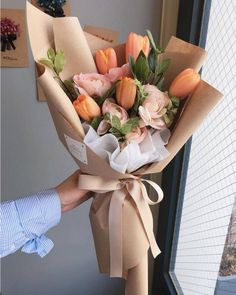 a person holding a bouquet of flowers in front of a window