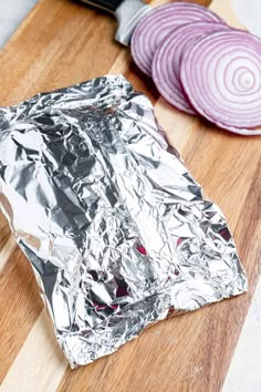 an aluminum foil wrapper with onions on a cutting board