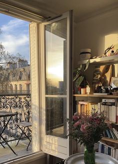 a vase filled with flowers sitting on top of a table next to a book shelf