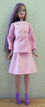 a doll with long purple hair wearing a pink dress and purple shoes is standing in front of a white wall